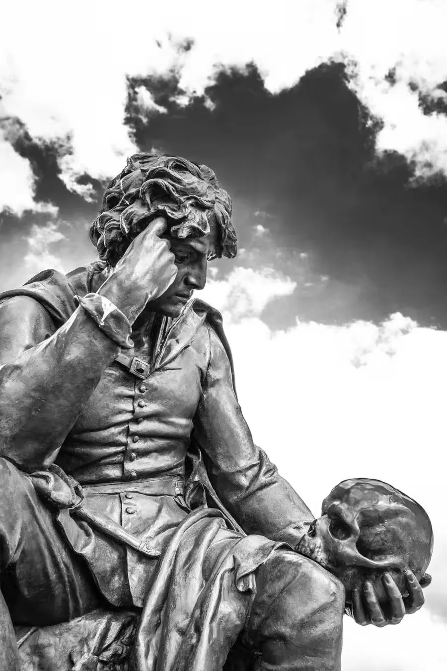 A statue of a man looking at a skull