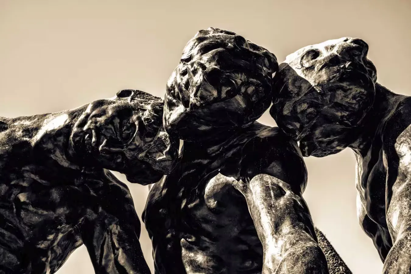 A statue of three persons leaning against one another